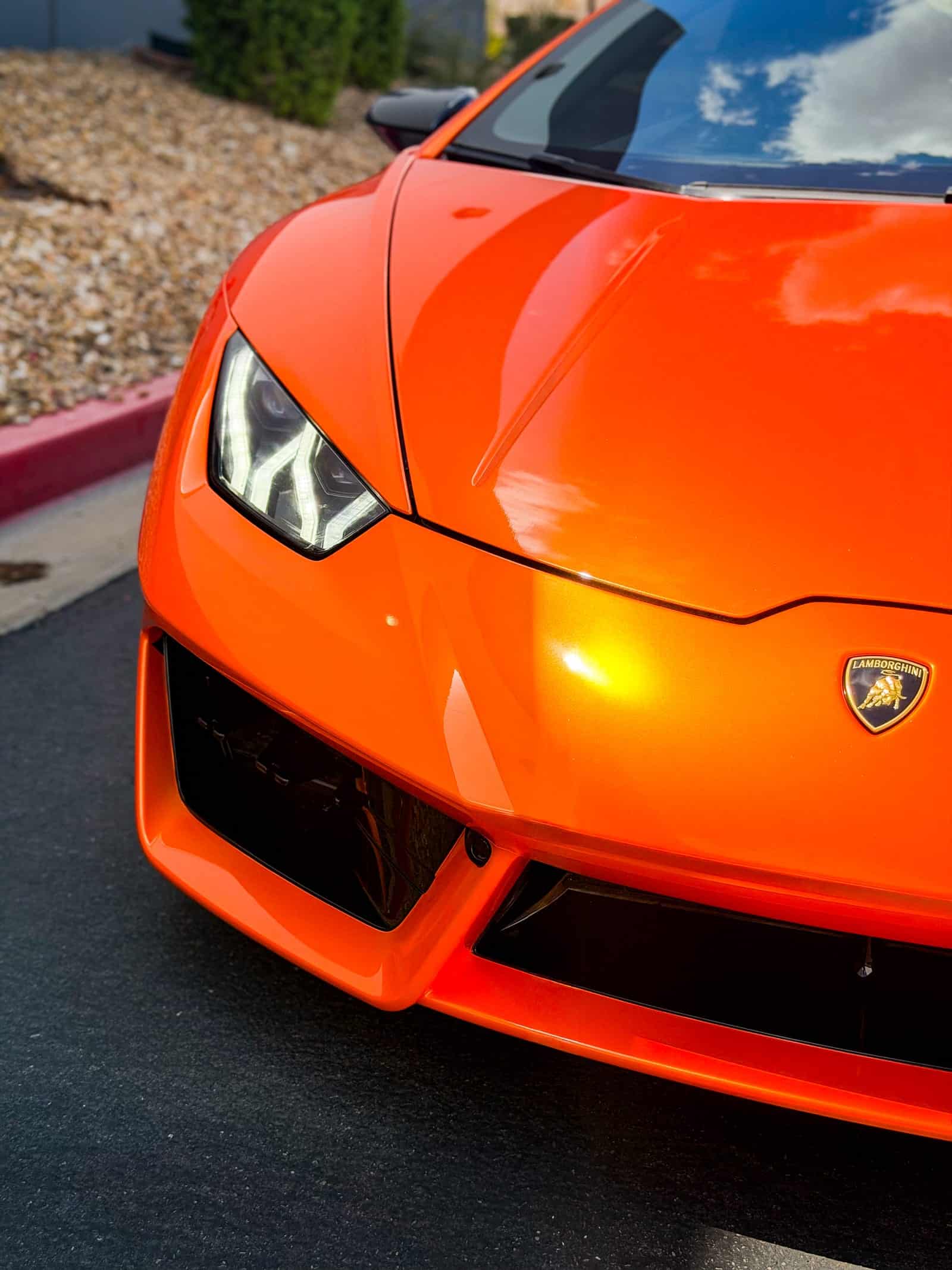 orange car wrap — close-up of the hood and headlight showing gold highlights in the orange vinyl